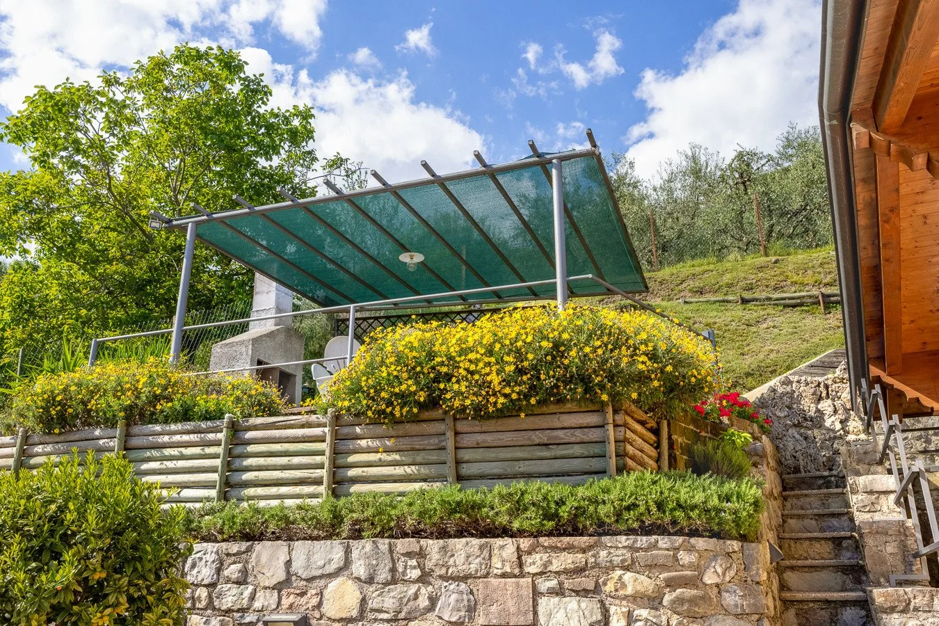 A landscaped outdoor terrace with a shaded seating area and stone steps.