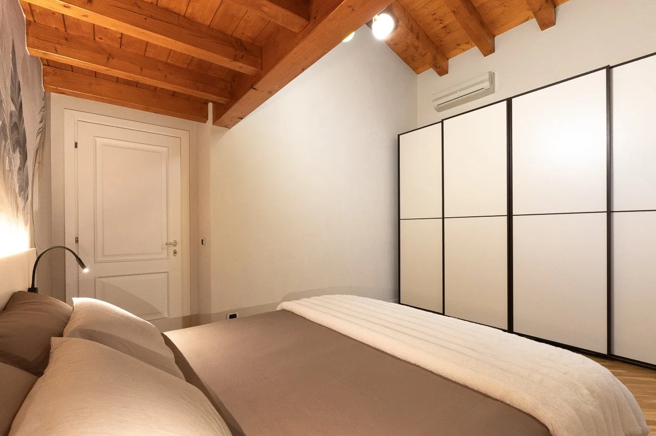 A bedroom with a bed, a white door, and built-in storage.