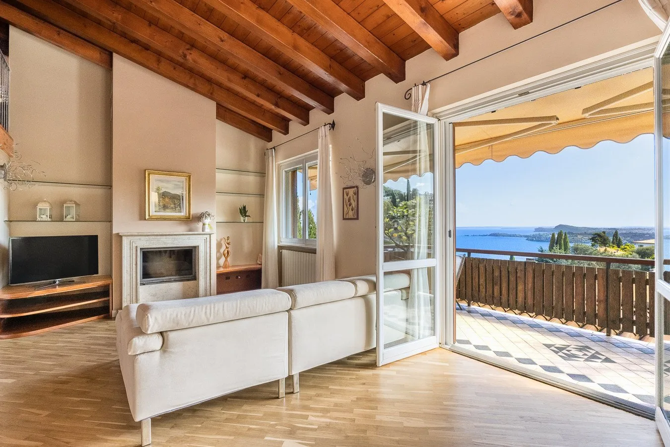 A living room opens onto a balcony with a view of the sea.