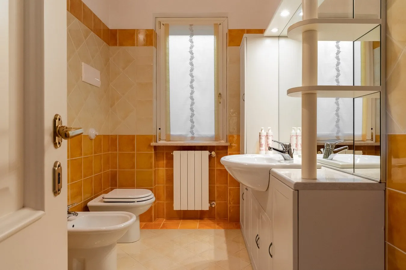 A bathroom with a toilet, sink, and vanity beneath a window.