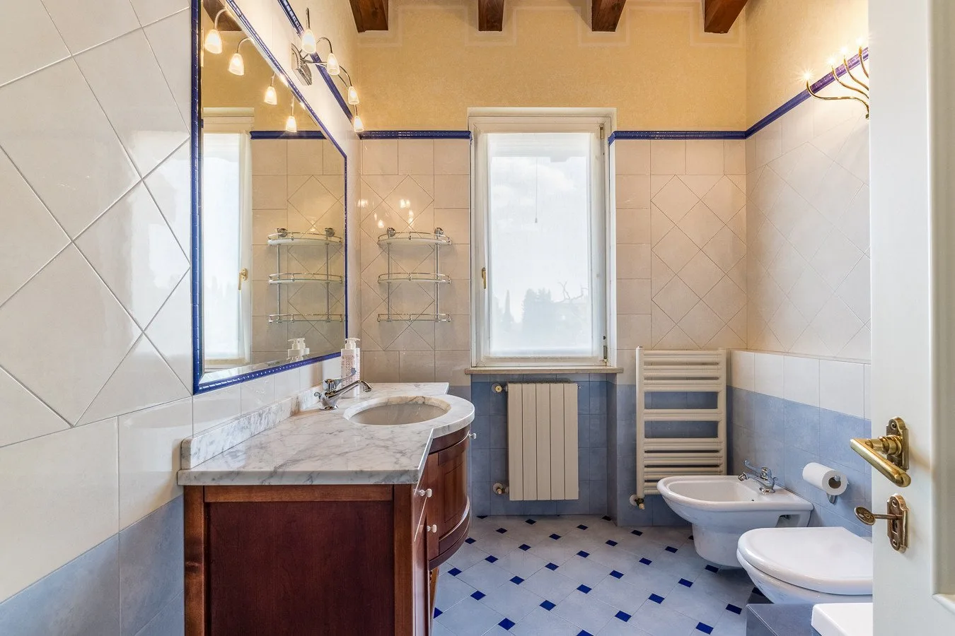 A tiled bathroom with a vanity, window, and bathroom fixtures.
