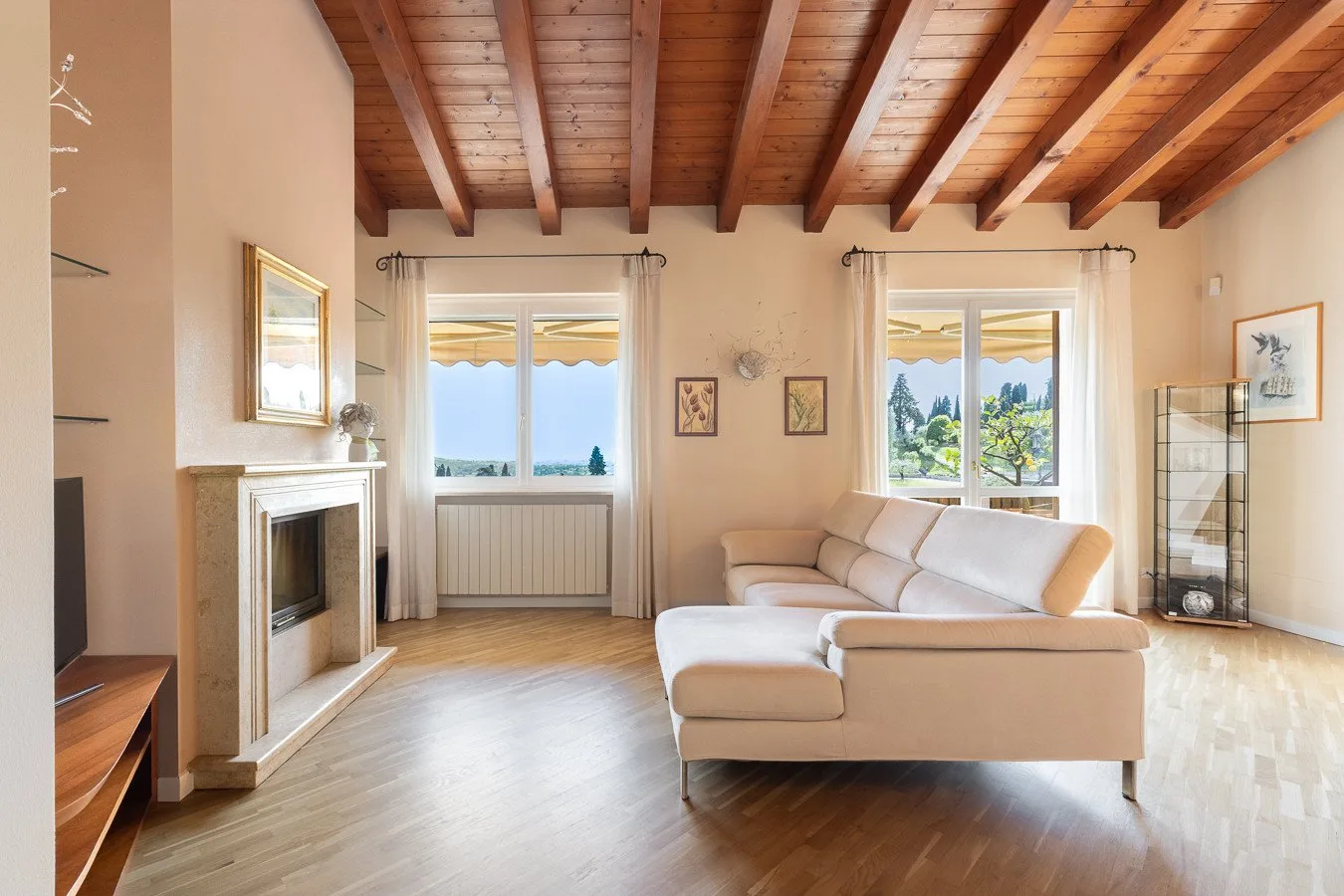 A bright living room with a light-colored sectional and a fireplace.