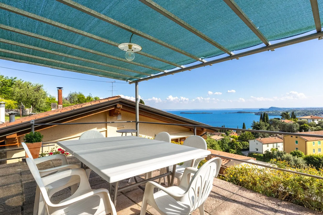 A covered outdoor dining area overlooks the sea, with a table and chairs beneath a canopy.