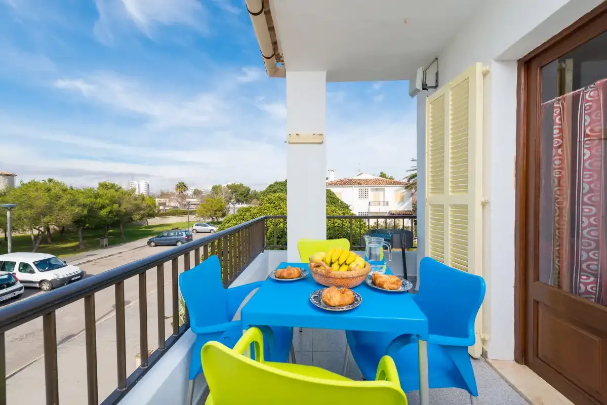A balcony dining area with a bright blue table and colorful seating overlooks the street.