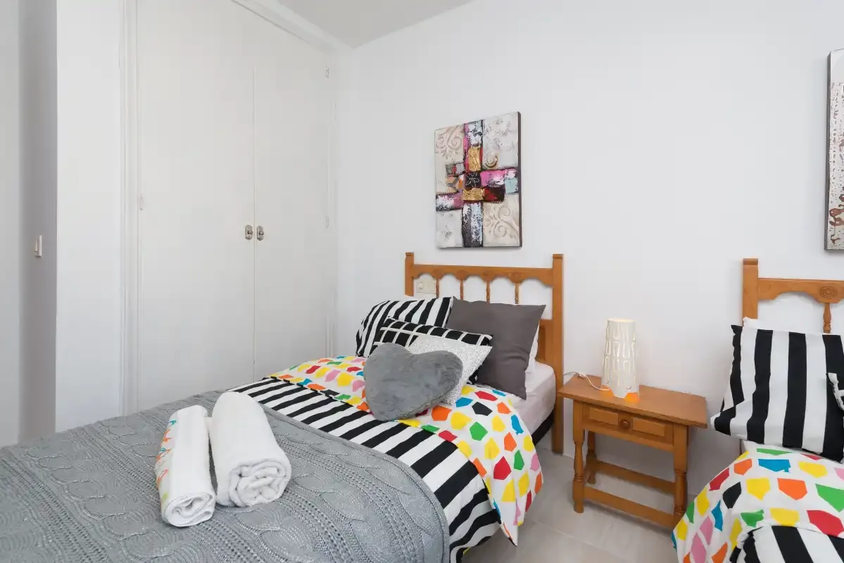 A bedroom with two beds dressed in colorful patterned bedding.