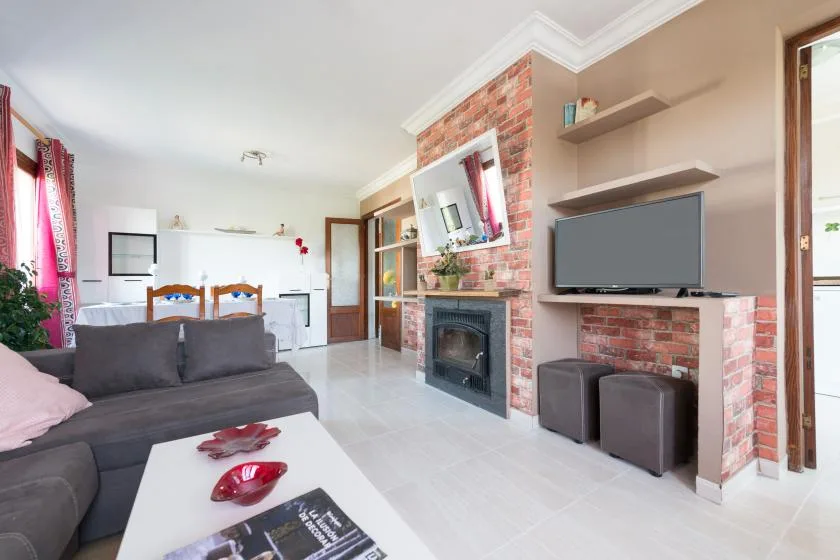 A living room with dark seating, a brick fireplace, and a television.