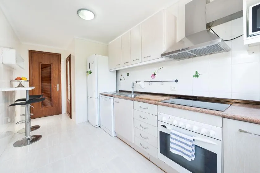A bright kitchen with white cabinets, a countertop, and built-in appliances.