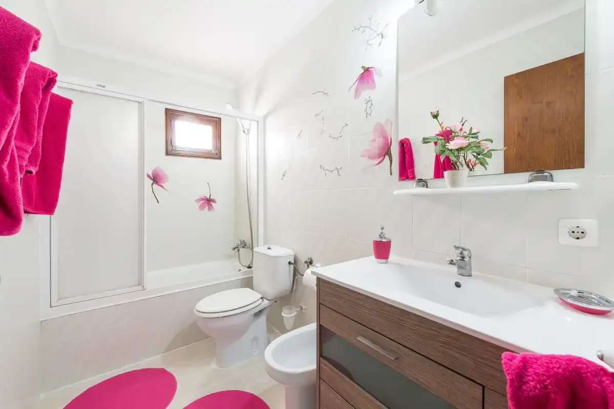 A bright bathroom with a shower, toilet, and sink.