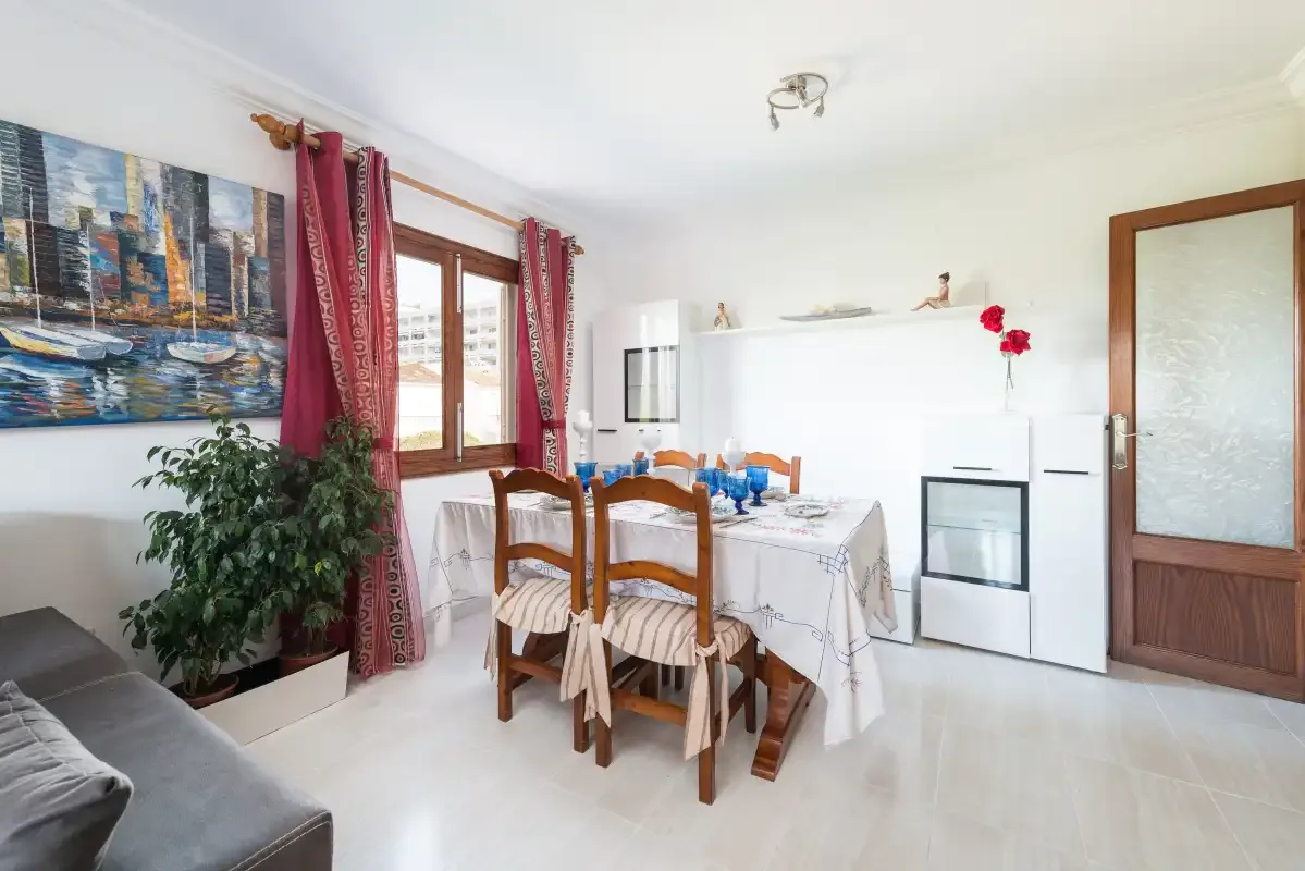 A dining area with a table set beside a window and a kitchen appliance.
