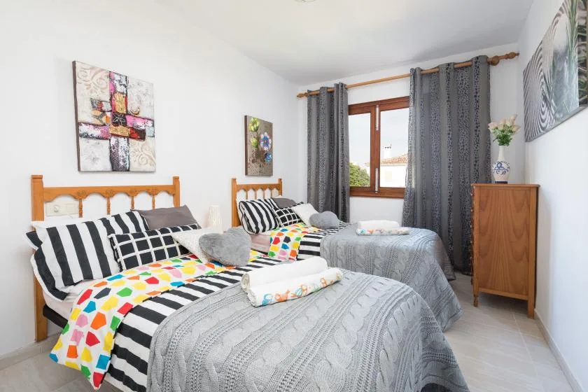 A bedroom with two beds dressed in patterned bedding and a window with curtains.