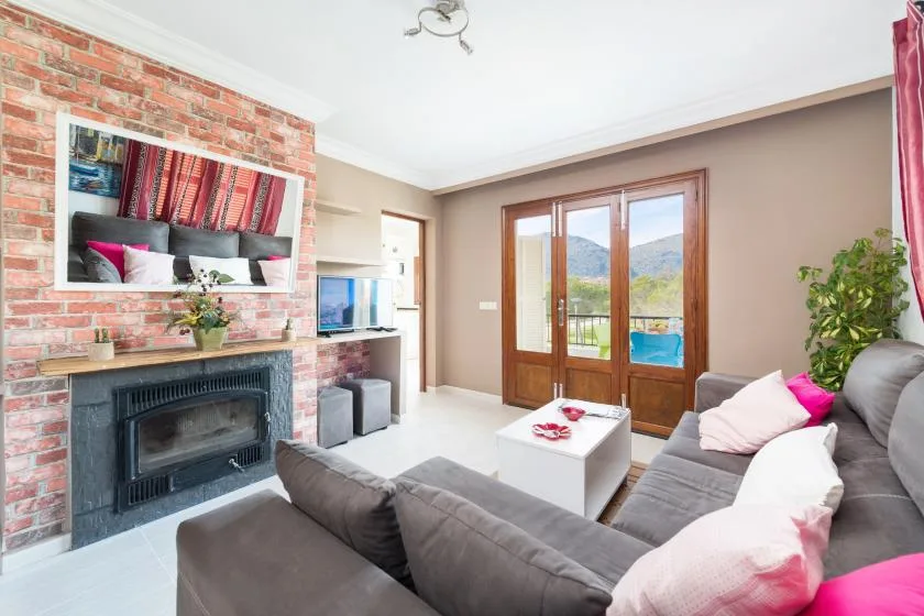 A living room with a brick fireplace and glass doors opening onto a balcony.