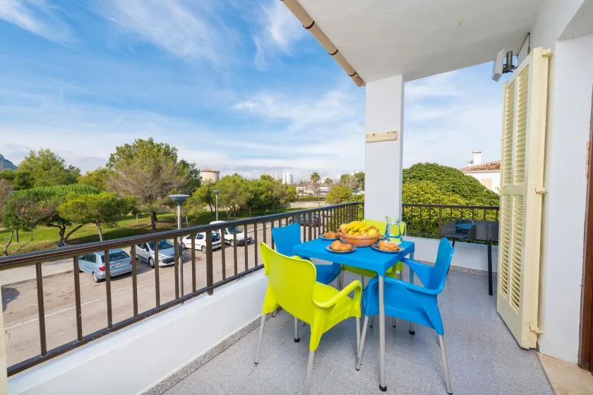 A balcony dining area with colorful chairs and a table overlooking greenery.