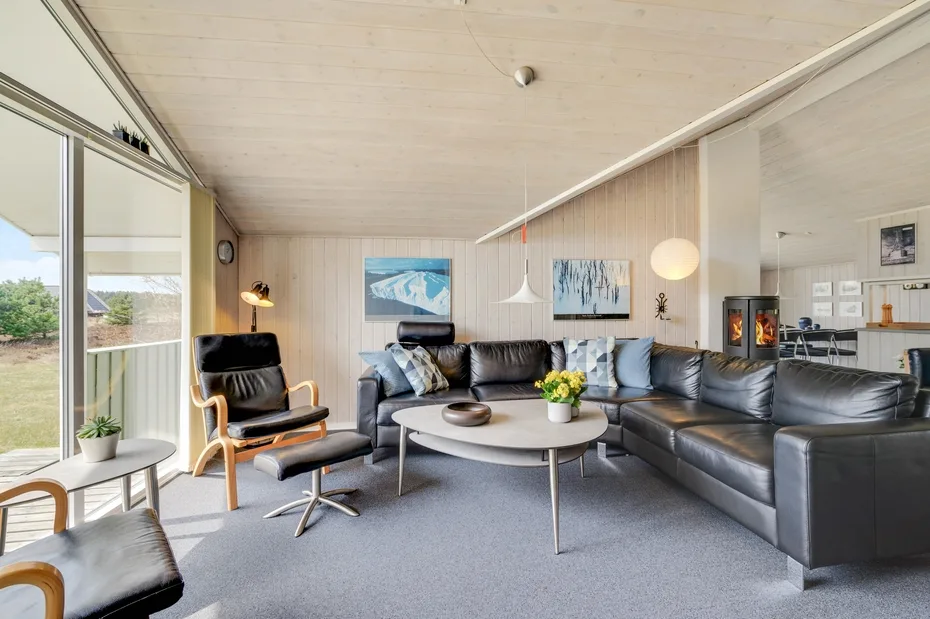 A bright living room with a leather seating area and large windows.