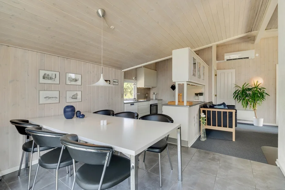 A dining area with a long table and several chairs beside the kitchen.