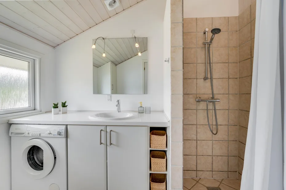 A bright bathroom with a sink, mirrored cabinet, and tiled shower.