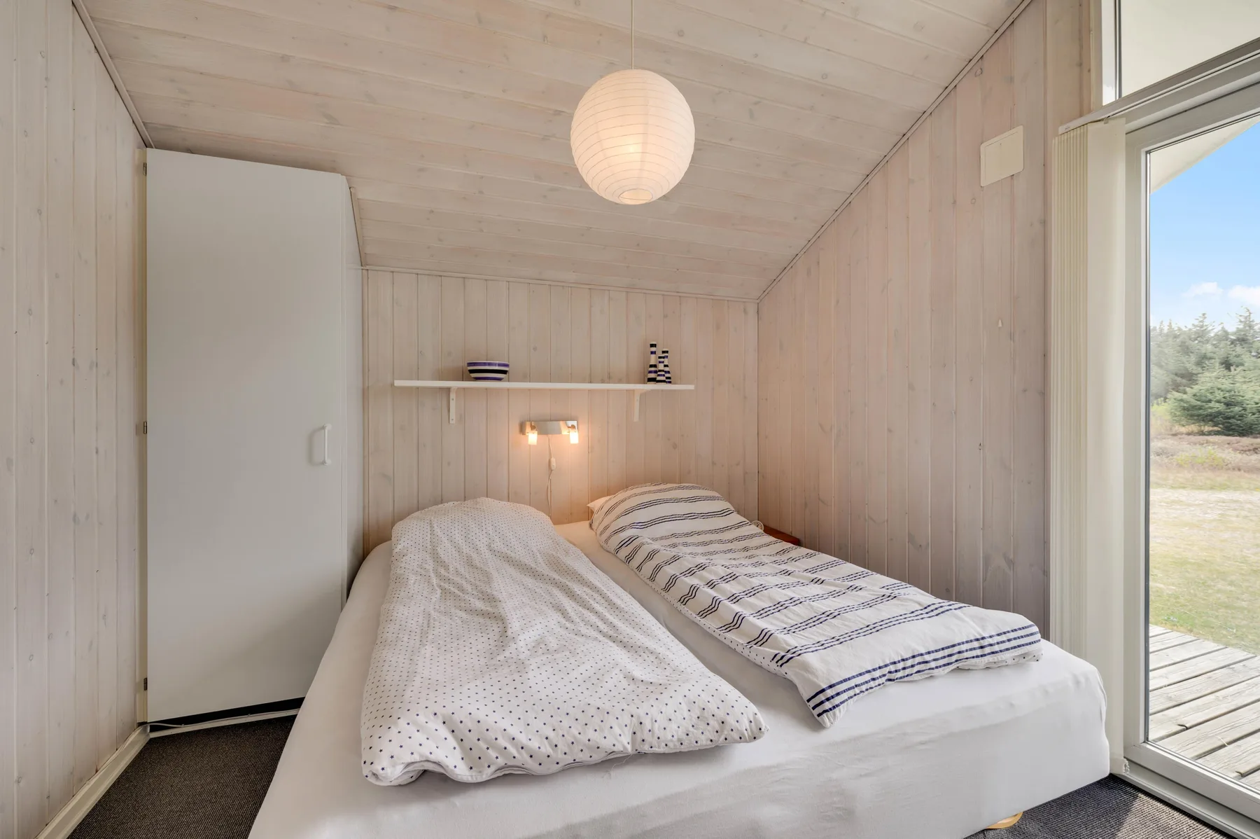 A small bedroom with two single beds beneath a hanging light.