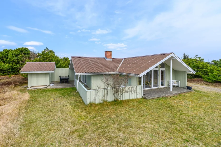 A single-story house with a covered patio stands in an open grassy yard.