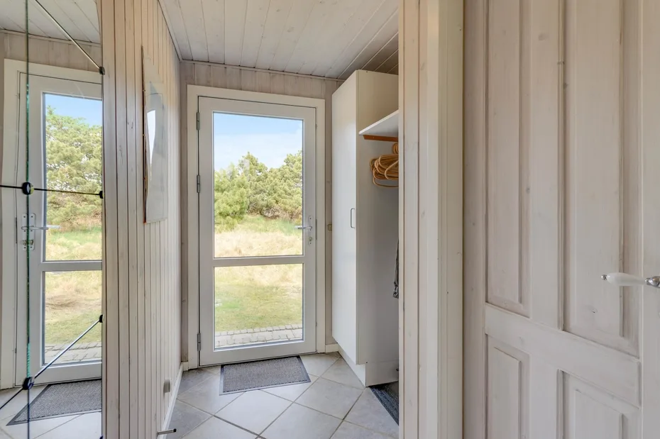A bright entryway with glass doors, tiled flooring, and a built-in coat area.