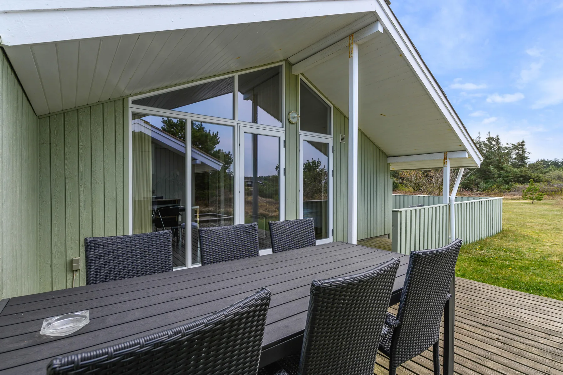 A covered outdoor dining area with a dark table beside the house.