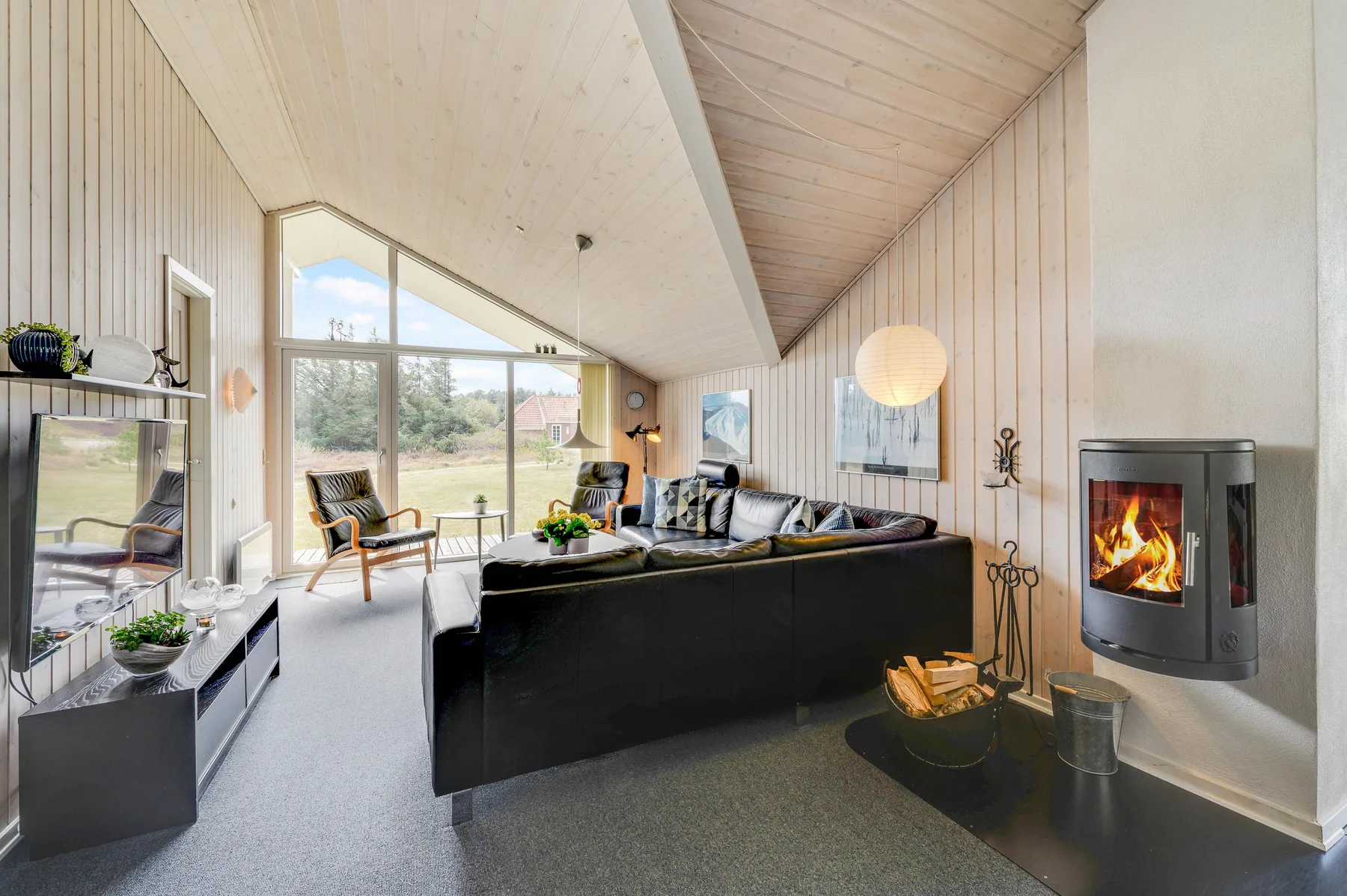 A bright living room with seating arranged around a fireplace and large windows.