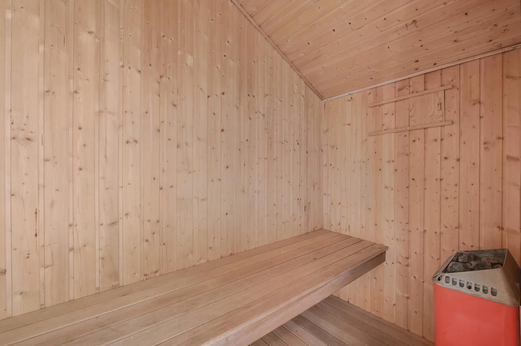 A wood-paneled sauna room with a long bench and a heater.