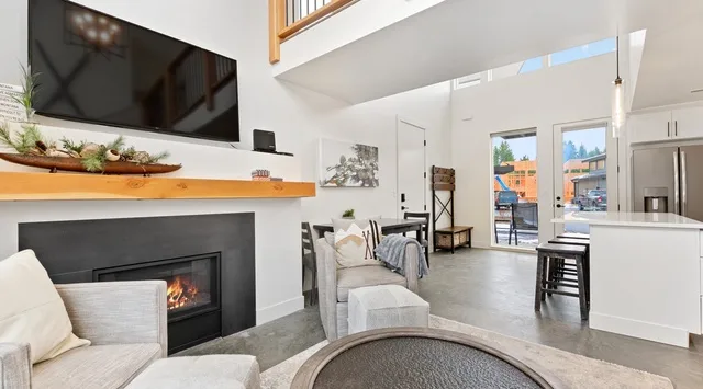 Una luminosa sala de estar abierta con chimenea, asientos e isla de cocina.