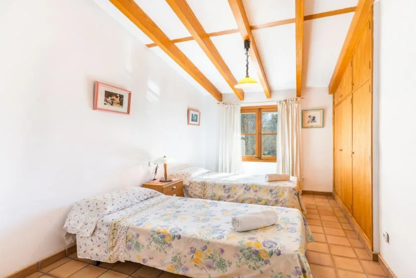 Un dormitorio luminoso con dos camas, armarios de madera y una ventana.