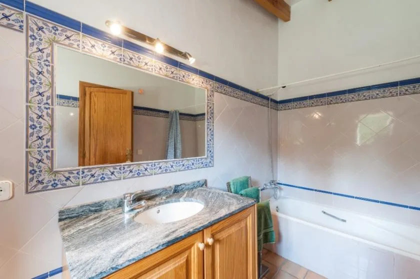 Un baño alicatado con bañera, lavabo y un gran espejo de pared.