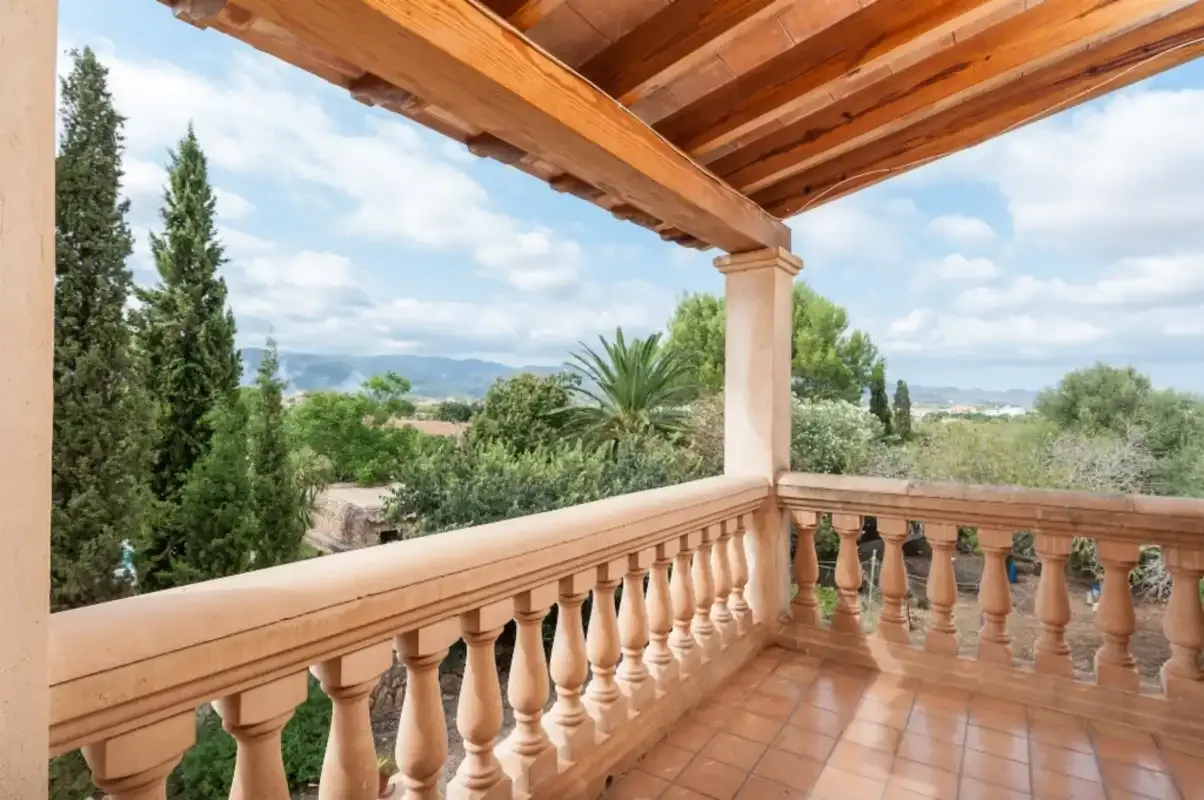 Una terraza cubierta da a árboles y colinas lejanas.