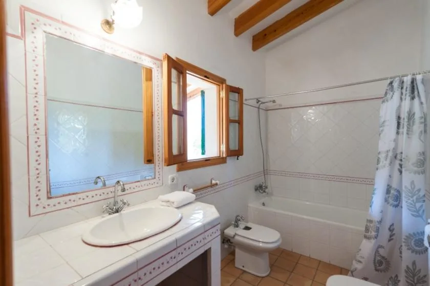 Un baño con lavabo, inodoro y bañera detrás de una cortina de ducha.