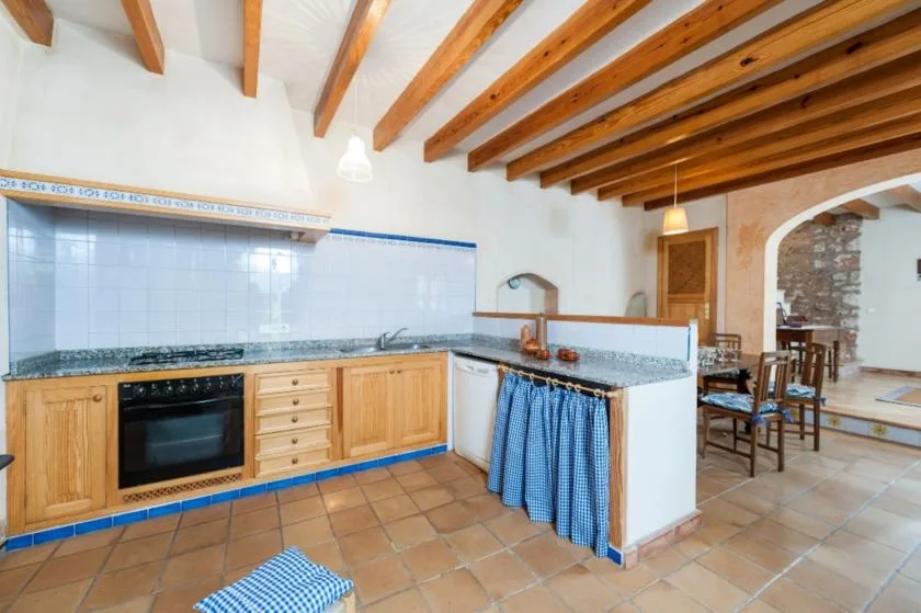Una cocina con suelo de baldosas, armarios de madera y una encimera junto a un comedor.