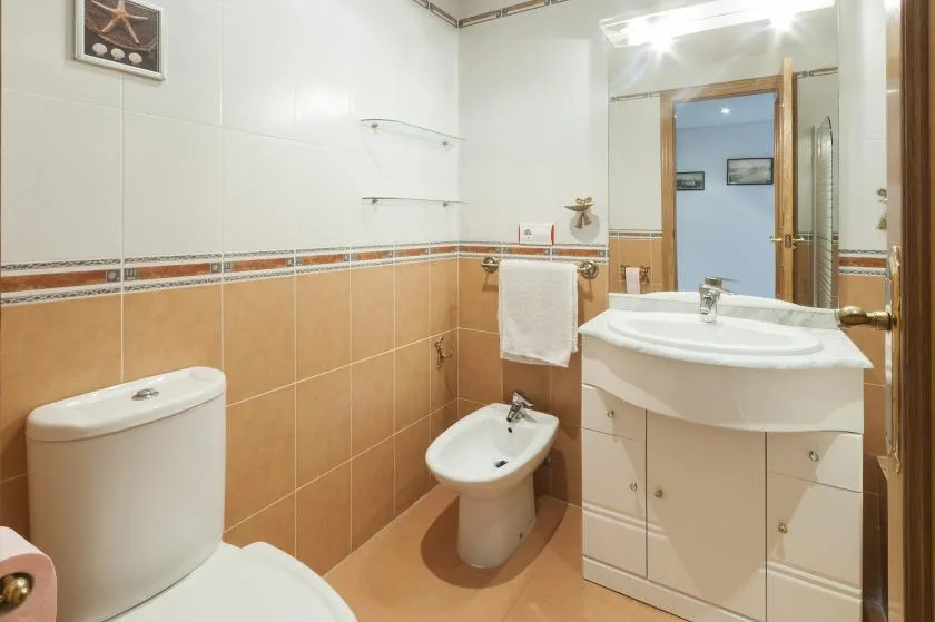 A tiled bathroom with a sink, toilet, and bidet.