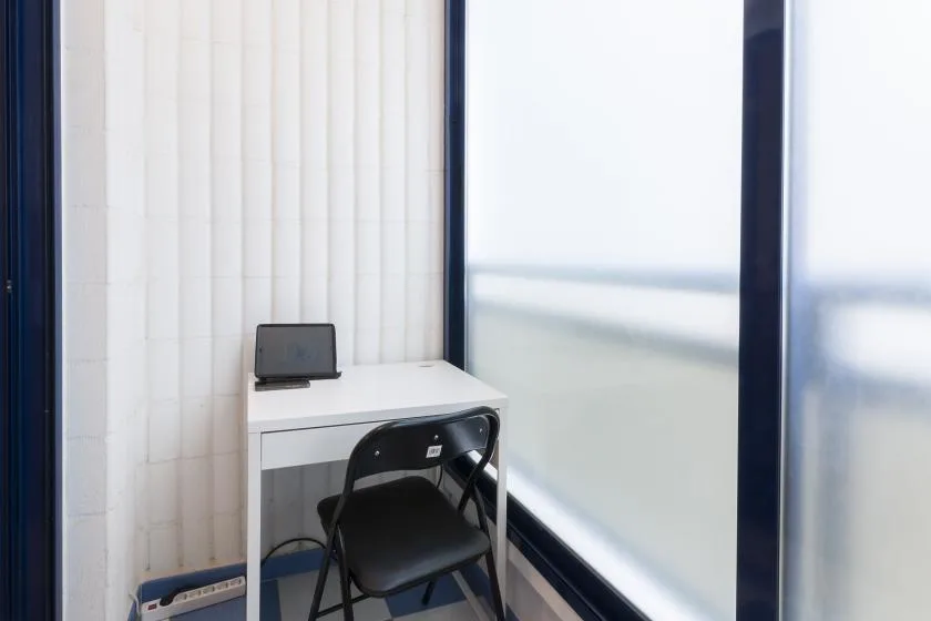 A compact desk and chair sit beside a large window.