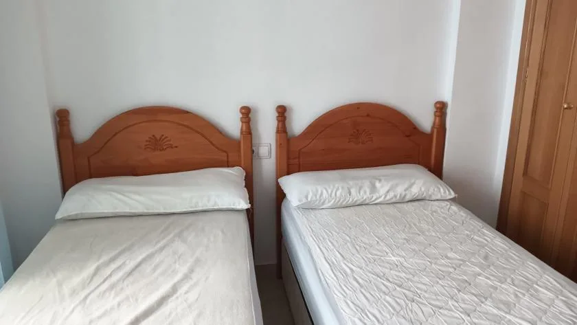 A bedroom with two single beds beside a wooden wardrobe.