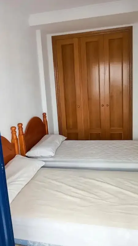 A bedroom with two beds and wooden wardrobe doors.