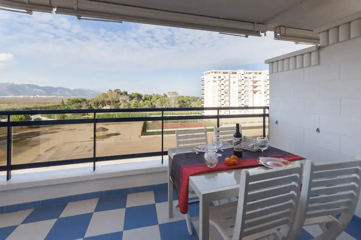 A balcony dining area with a table and chairs overlooking the landscape.