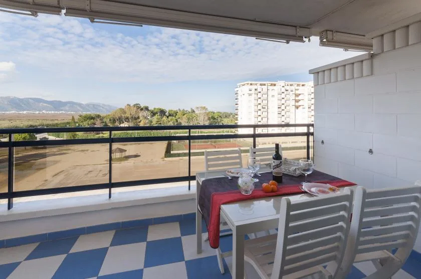 A balcony dining area overlooks a tree-lined landscape and distant mountains.
