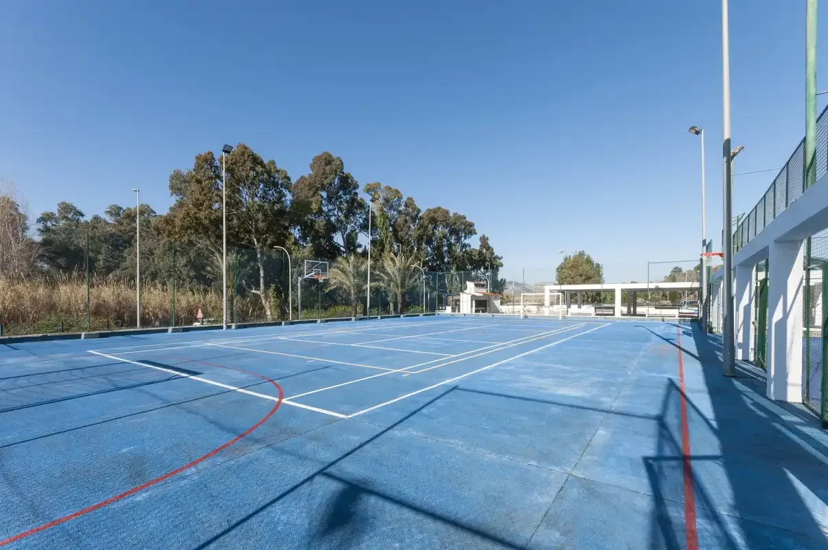 An outdoor sports court with blue playing surfaces and basketball hoops.