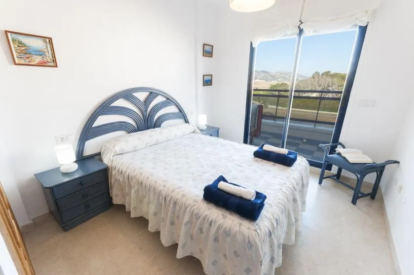 A bright bedroom with a bed and glass doors opening onto a balcony.