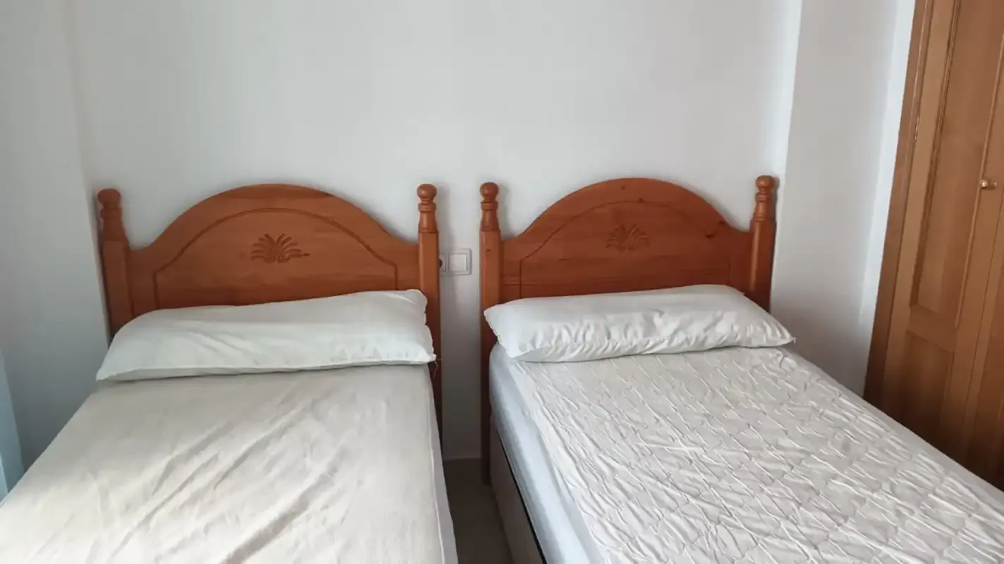 A bedroom with two single beds and white bedding.