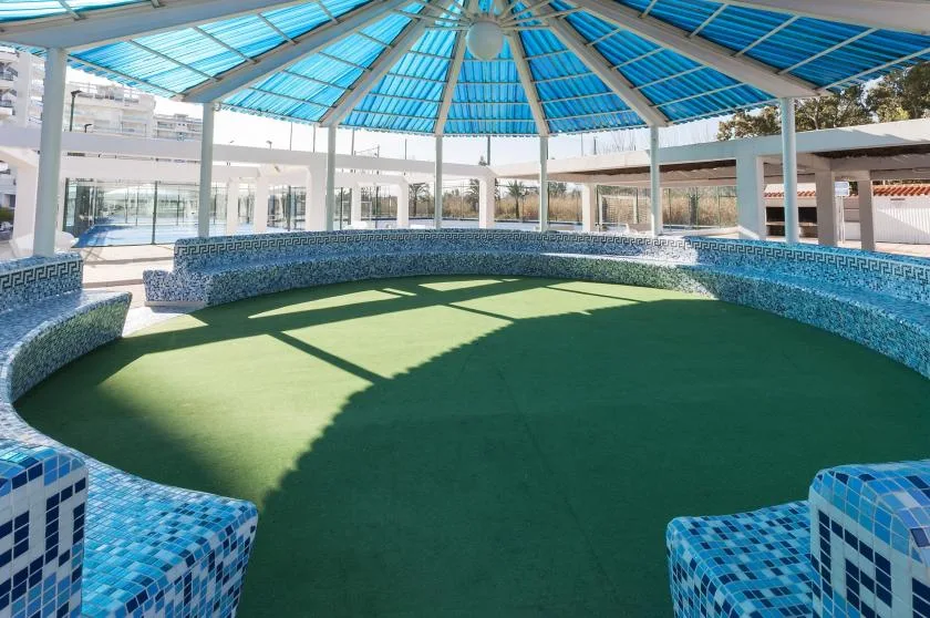 A circular covered pool area with blue-tiled seating around the edge.
