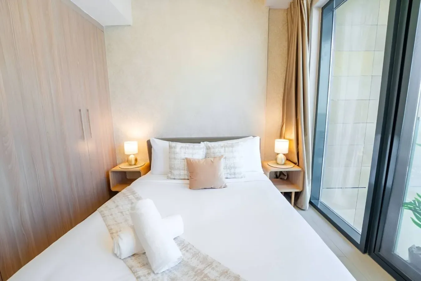 Un dormitorio luminoso con una cama bien tendida junto a grandes ventanales.