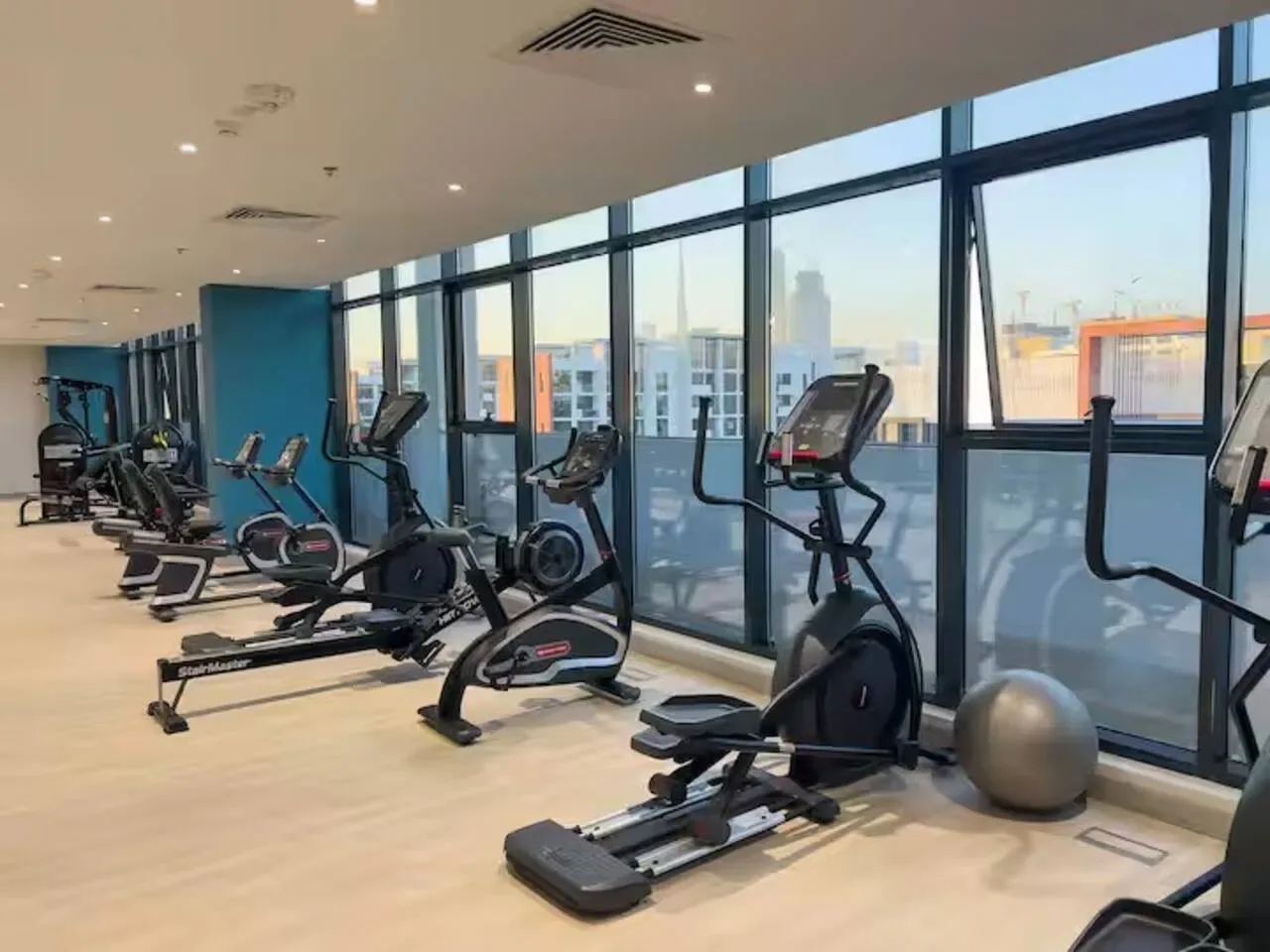 Un gimnasio con máquinas de ejercicio junto a grandes ventanales.