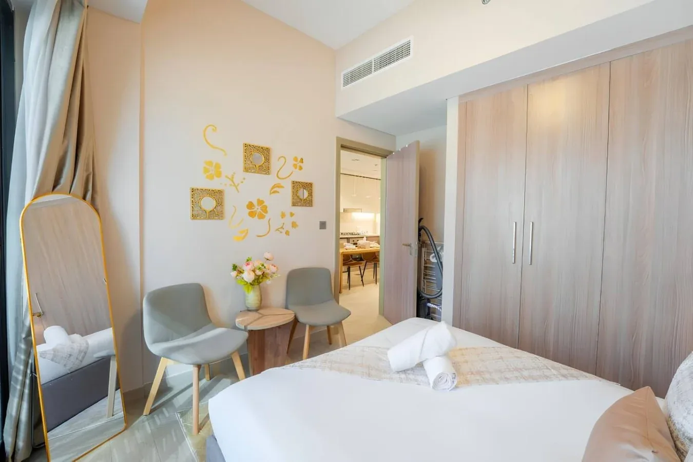 Dormitorio con una cama, dos sillas y adornos florales en la pared.