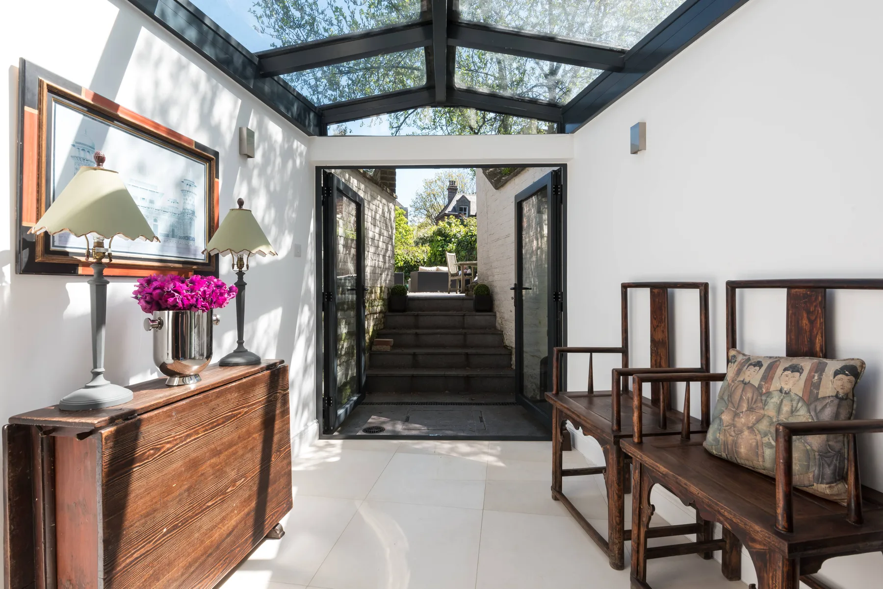 Una luminosa sala con techo de vidrio se abre a un patio ajardinado.
