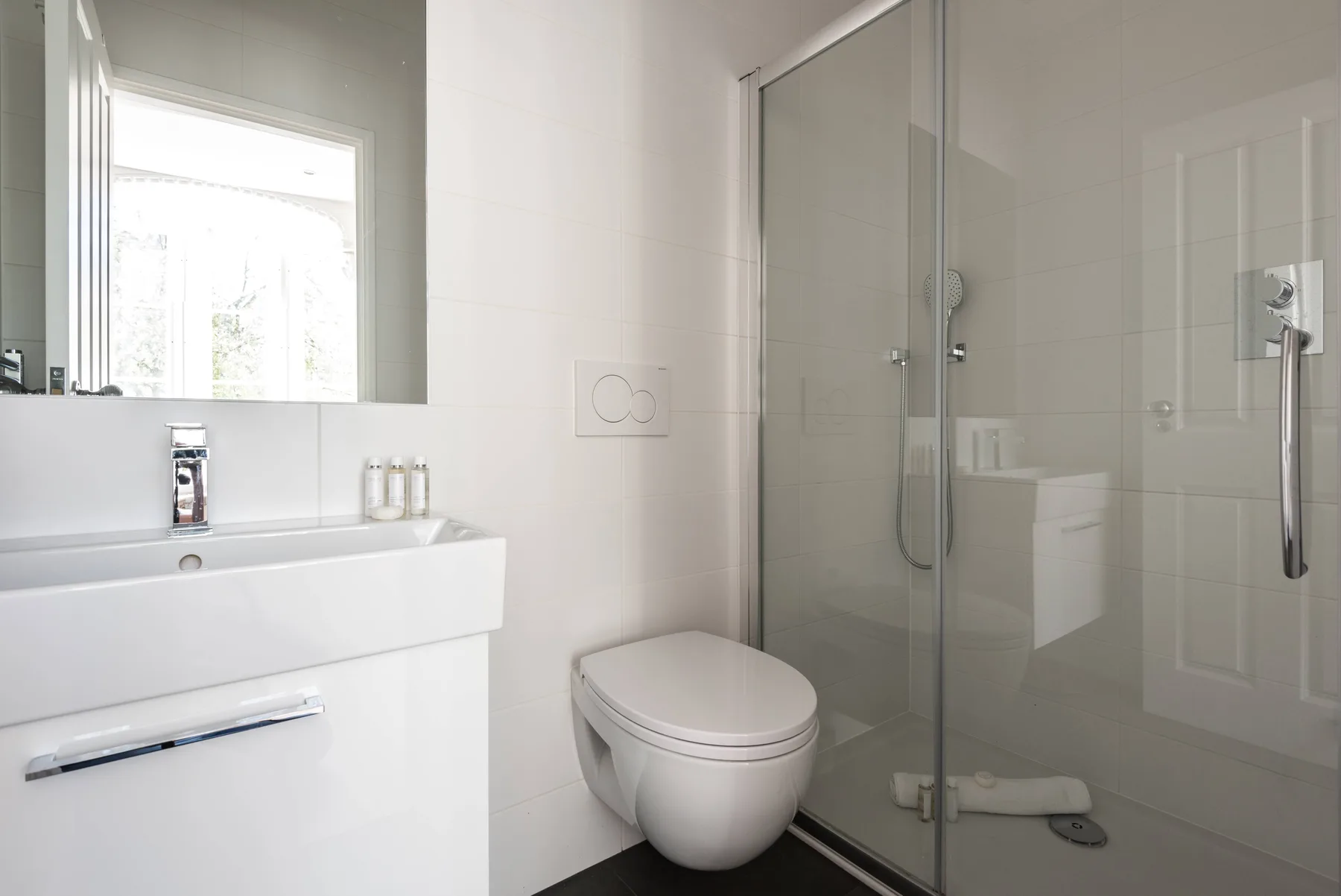 Un baño luminoso con lavabo, inodoro y ducha de vidrio.