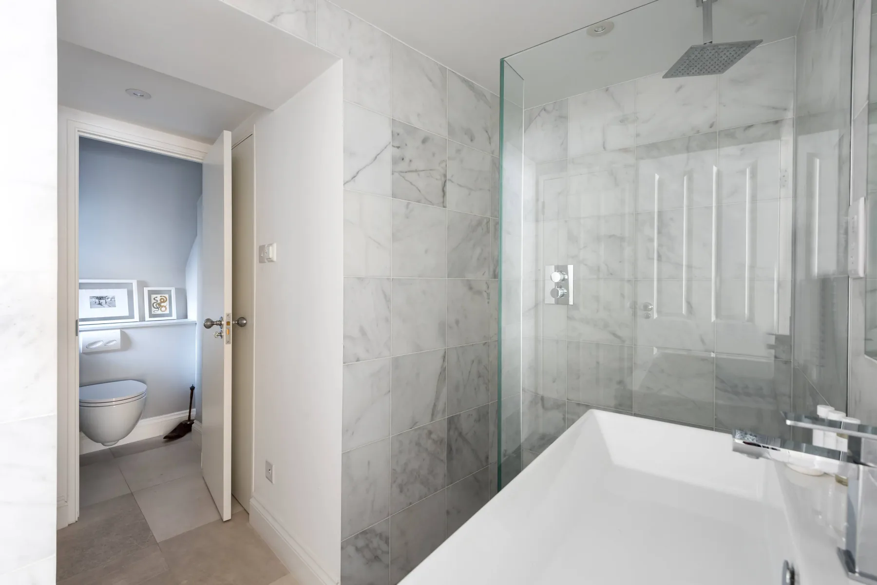 Un baño luminoso con bañera y ducha con mampara de vidrio.