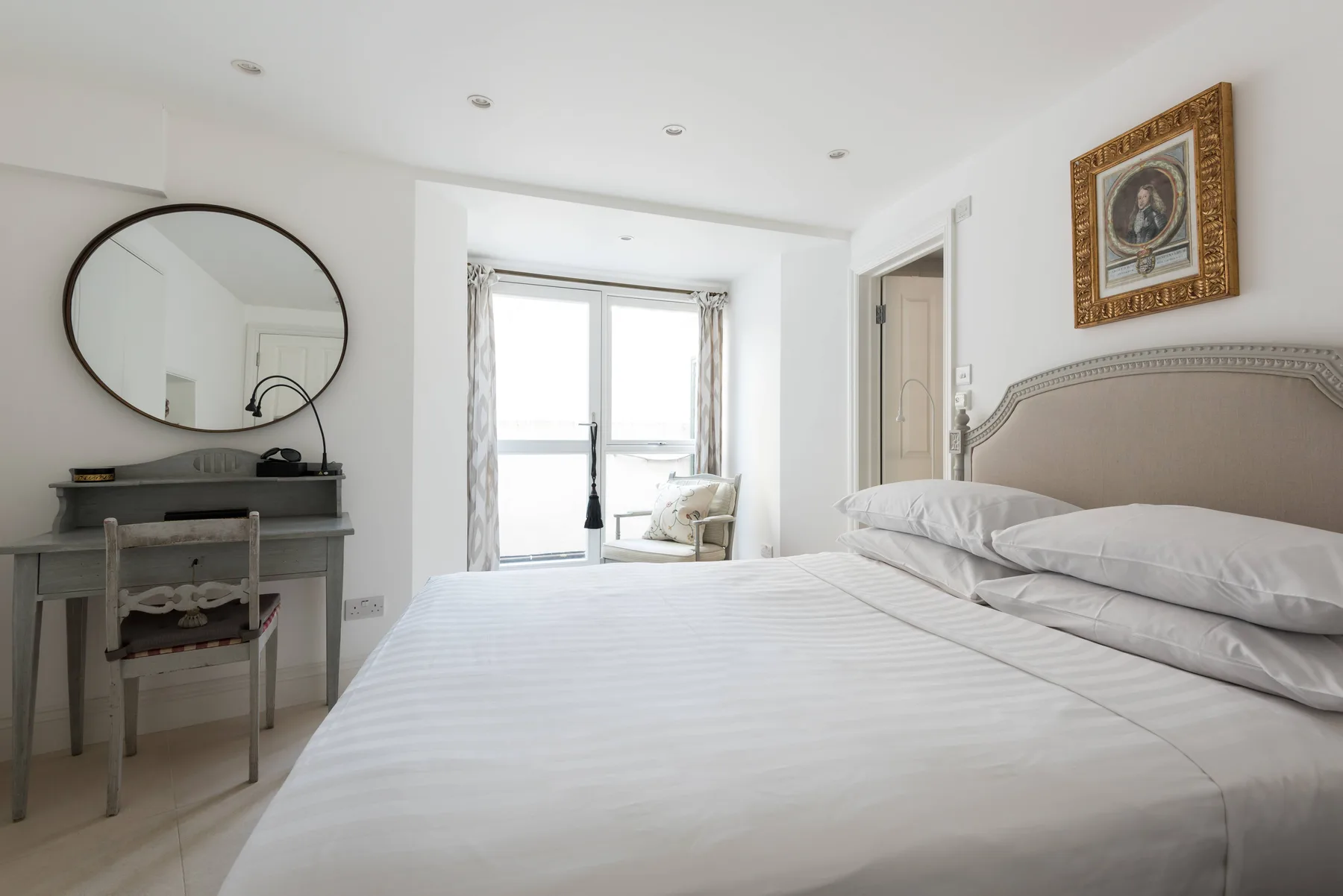 Un dormitorio luminoso con una cama hecha y un escritorio junto a la ventana.