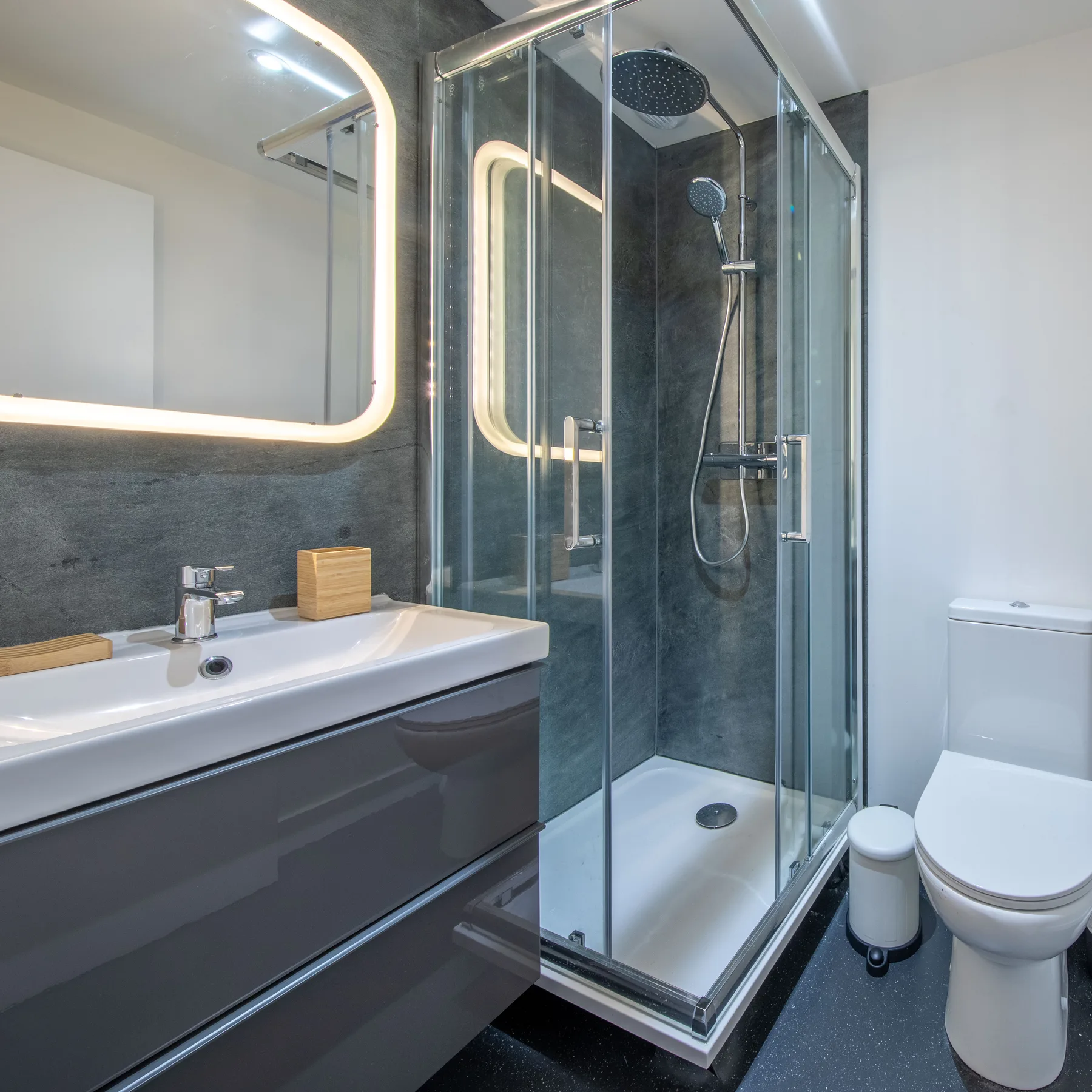 A modern bathroom with a sink, shower, and toilet.