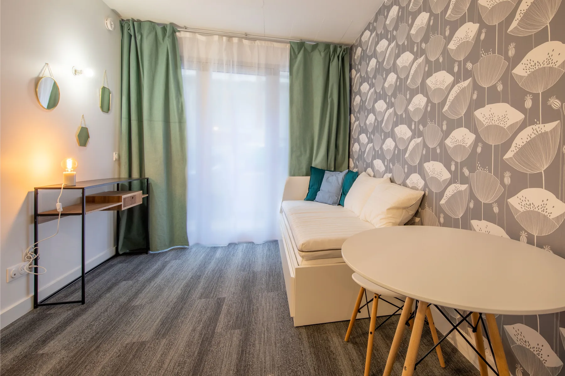 A furnished room with a sofa, round table, and green curtains.
